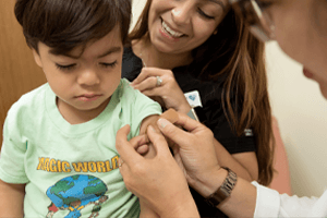 Young Boy Getting A Bandaid Put On His Shoulder By A Doctor