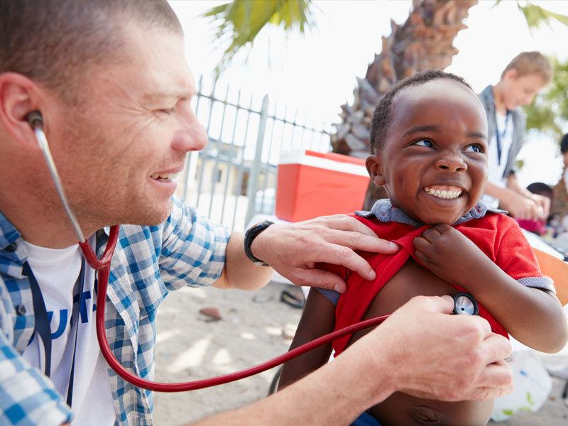 Older Man Using A Stethoscope On Young Boy